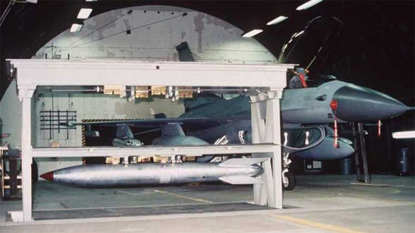 A missile stored in a hangar next to a fighter jet
